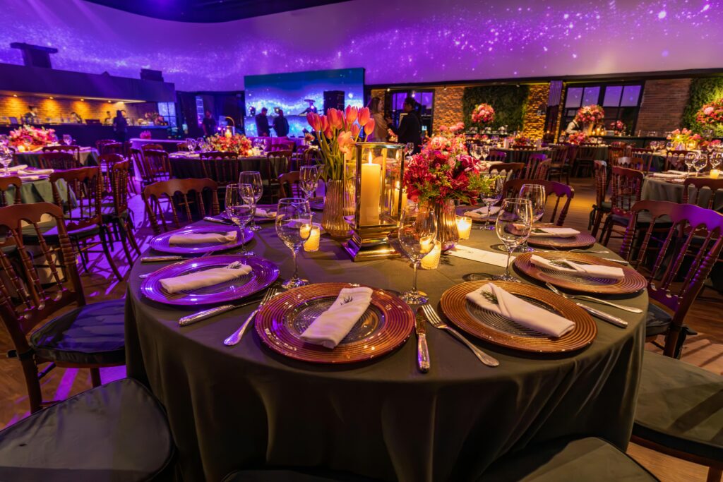pexels-photo-16935897-16935897 Stunning wedding reception with elegant table settings and floral centerpieces under a glowing ceiling.