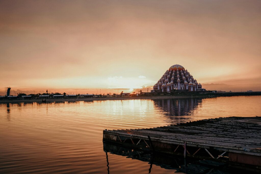 pexels-photo-2355062-2355062 Capture of Makassar's Floating Mosque at sunset reflecting over calm waters.